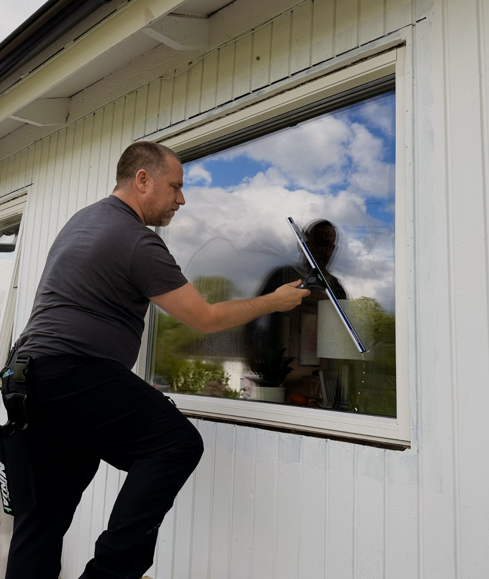 Kristopher på stege som putsar ett fönster på ett bostadshus