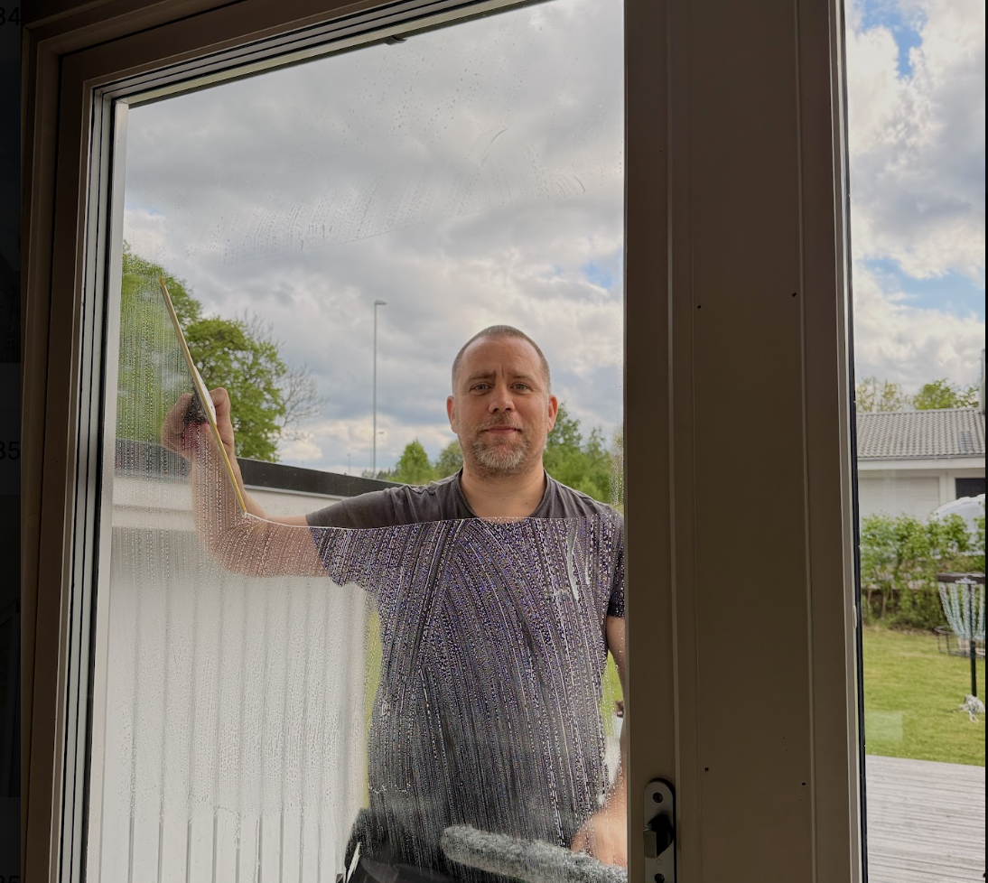 Kristopher putsar en stor glasdörr hos ett företag